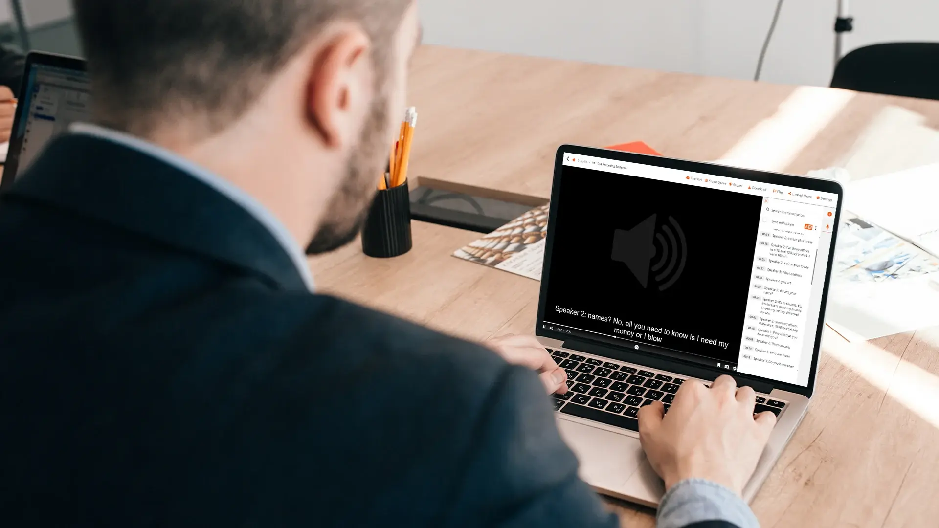 A reviewer at a laptop with an audio file open on screen