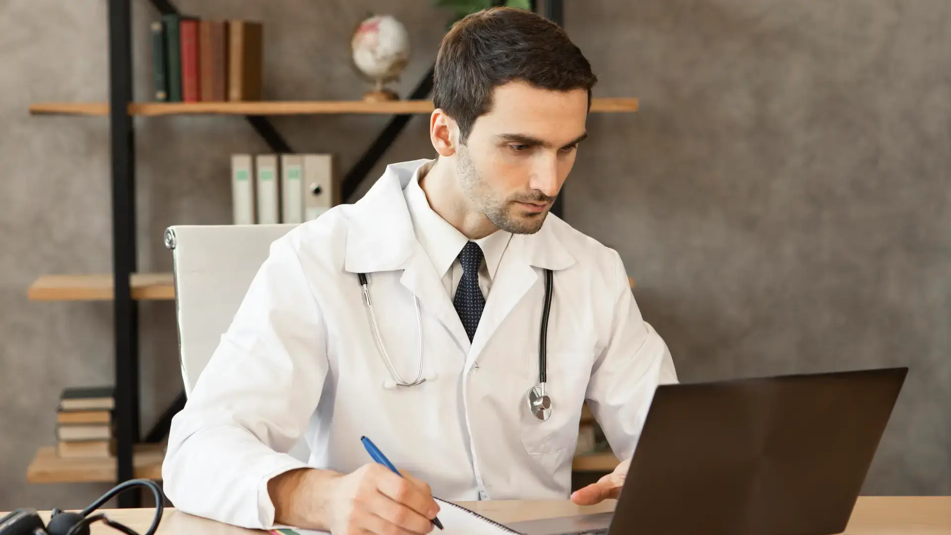a doctor looking at the laptop screen having a pen in his hand